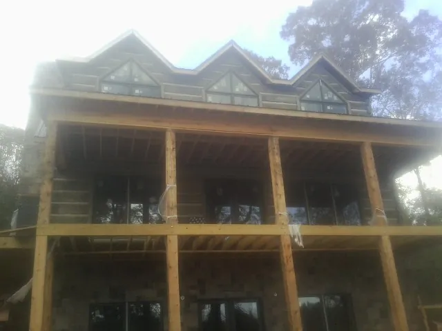 Dormers and porch framing on a large log home under construction — Roof Coating work by our crew in Sawyer