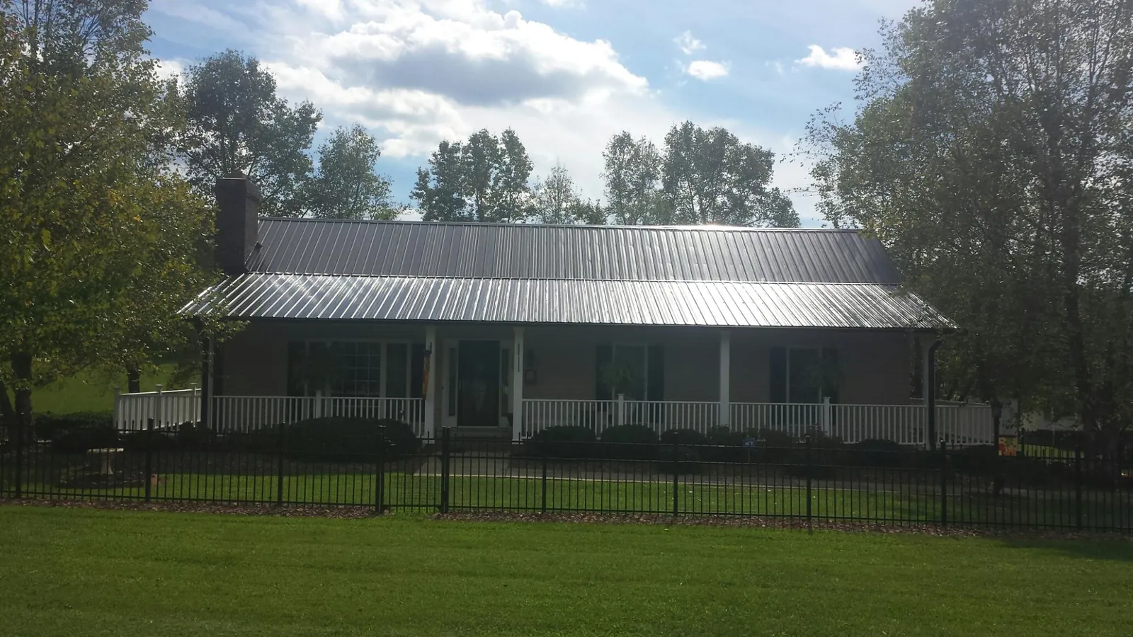 Gray metal roof on a brick ranch with a full width front porch — Gutter Guard Installation work by our crew in Sawyer