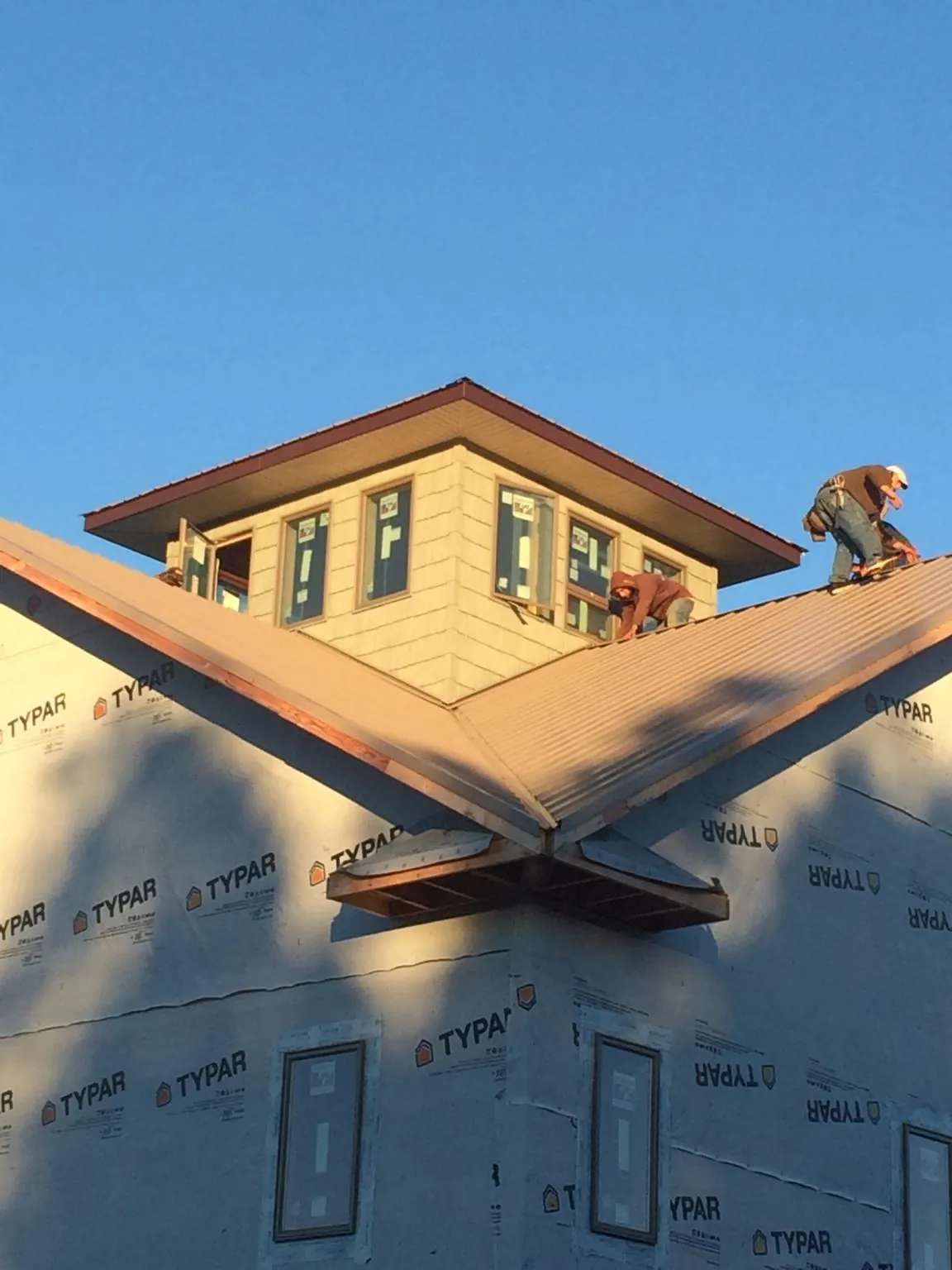 Roofers working around a rooftop cupola on a new metal roof at sunset — Roof Waterproofing in Sawyer by Roofing Brothers